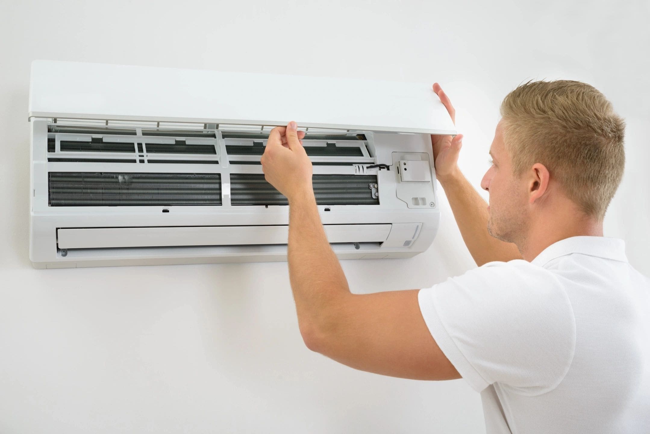 A man is fixing the air conditioner on the wall.